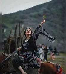 A Kurdish woman from Rojhelat (Kurdistan in Iran) raises a red rose — as a symbol of resistance — during Newroz celebrations in Merîwan, 2023. Photo: Erfan Salehi/Instagram.